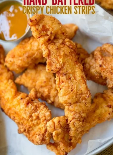 Crispy chicken tenders served with dipping sauce on a plate.