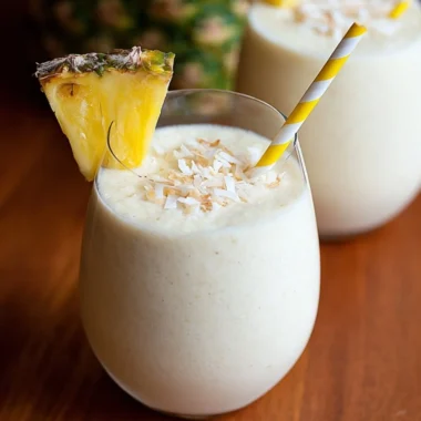 Easy 3 ingredient Piña Colada Smoothie in a glass with pineapple and coconut.