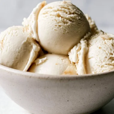 Bowl of creamy homemade coconut ice cream topped with coconut flakes