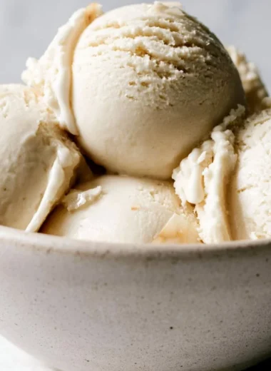Bowl of creamy homemade coconut ice cream topped with coconut flakes