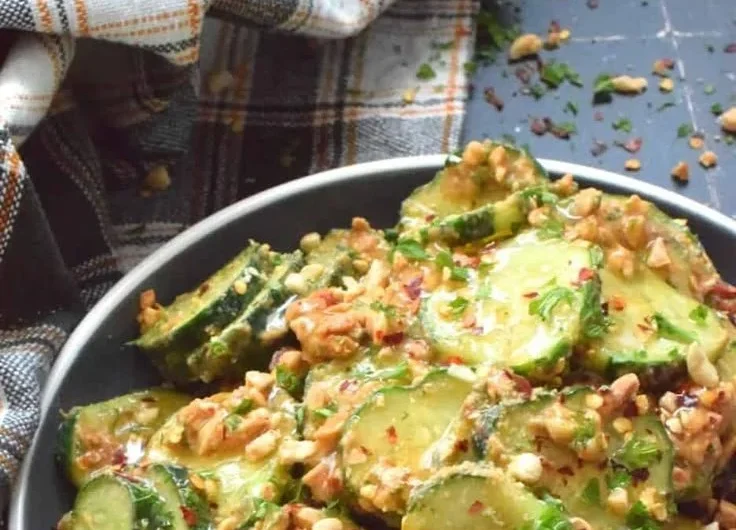 Cucumber salad drizzled with creamy peanut sauce served in a bowl