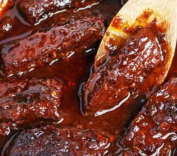 Deliciously plated Korean Braised Short Ribs with rich sauce and garnish.