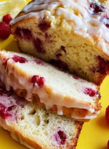 Sliced Raspberry Lemon Loaf with a drizzle of lemon glaze on a wooden board