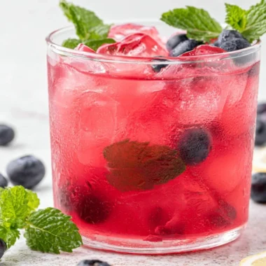 Cup of antioxidant-rich blueberry green tea with fresh blueberries and green tea leaves.