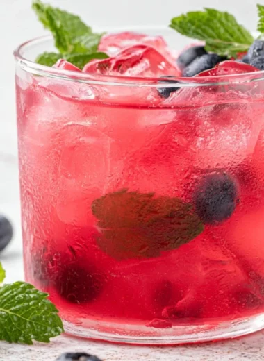 Cup of antioxidant-rich blueberry green tea with fresh blueberries and green tea leaves.