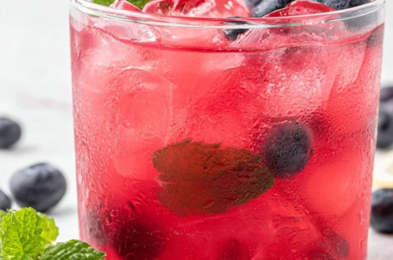 Cup of antioxidant-rich blueberry green tea with fresh blueberries and green tea leaves.