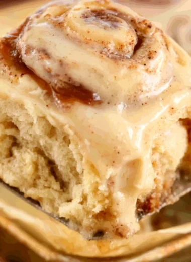 Apple Butter Cinnamon Rolls topped with icing on a wooden table.