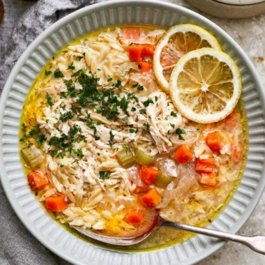 Bowl of cozy Greek lemon chicken soup garnished with fresh herbs