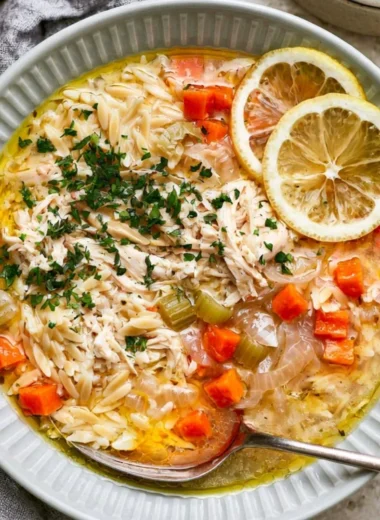 Bowl of cozy Greek lemon chicken soup garnished with fresh herbs
