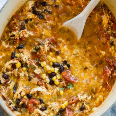 Bowl of easy chicken tortilla soup garnished with tortilla strips and avocado.