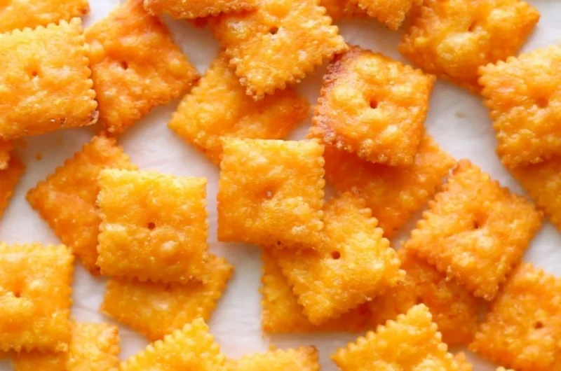 Homemade cheese crackers on a wooden platter, perfect for snacking.