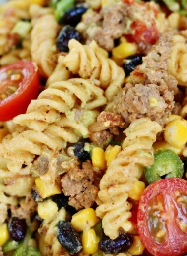 A vibrant bowl of cozy taco pasta salad with colorful toppings and ingredients.